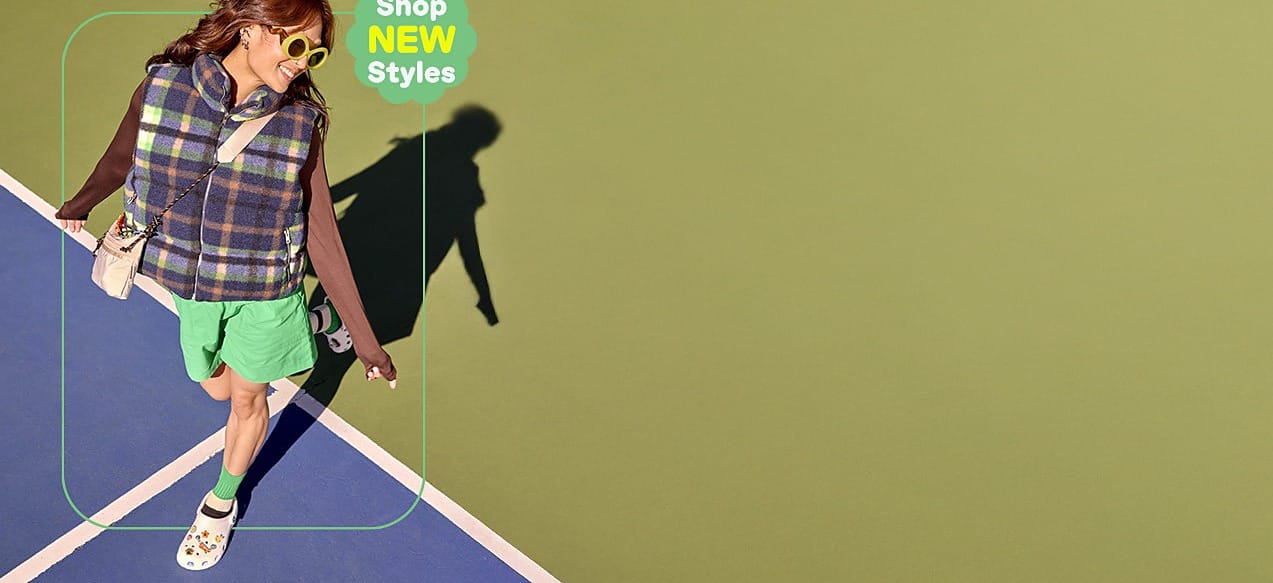 A person wearing white Crocs clogs walking across a tennis court in a brand campaign photograph - the clog and sandal categories this Crocs India August 2026 price read covers, from Rs. 1,797 to Rs. 4,197