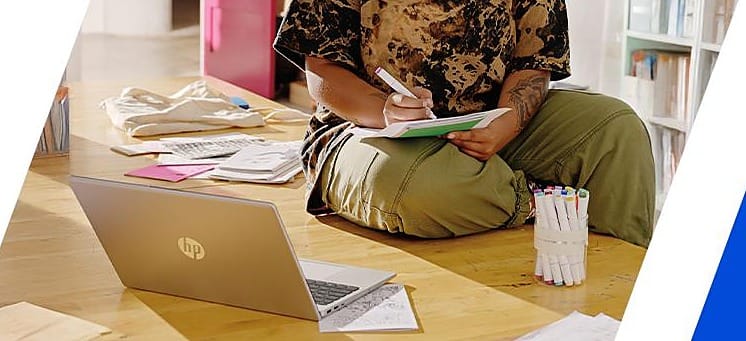 A student working through notes beside an open laptop, from HP's own laptop campaign photography - the online-course context this page prices