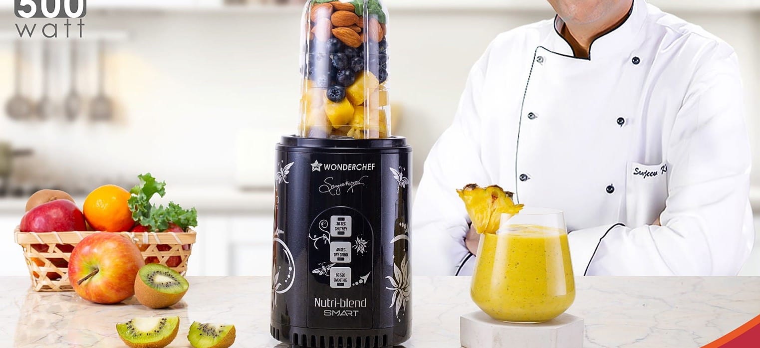 A mixer-grinder blender jar filled with fruit on a kitchen counter beside a prepared smoothie - the kitchen appliance aisles this Reliance Digital August 2026 price read covers, from Rs. 1,199 mixers to Rs. 57,752 microwaves