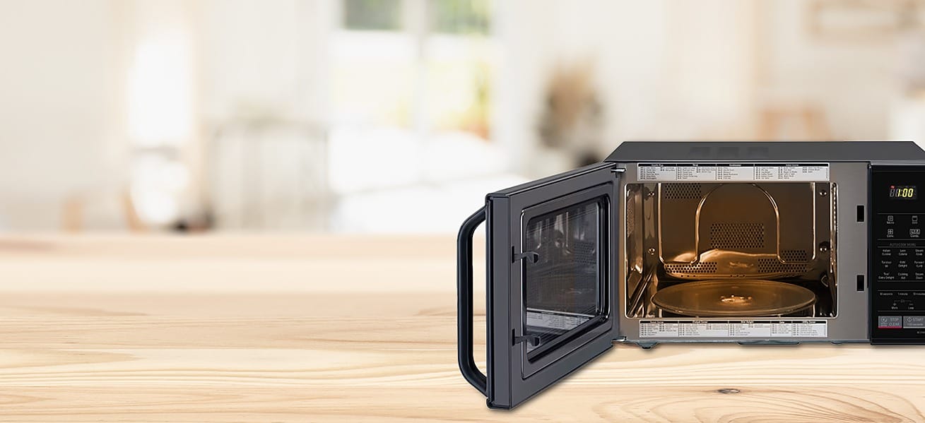 A microwave oven with its door open on a wooden kitchen counter - the microwave category this Reliance Digital August 2026 price read covers, from Rs. 4,988 to Rs. 17,990